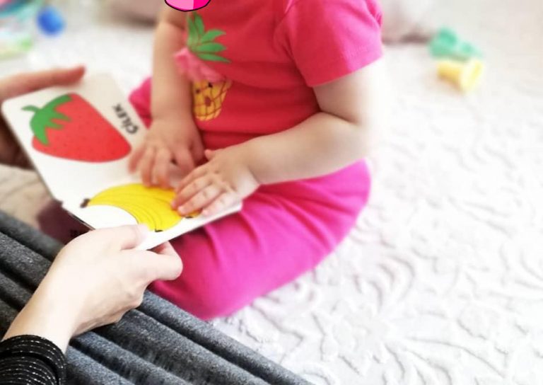 Bir yetişkinle birlikte resimli kitaba bakan çocuk