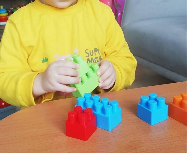 Renkli blokları bir araya getiren çocuk